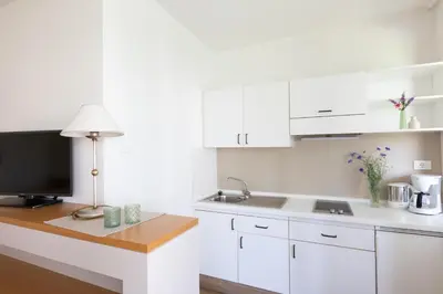 a kitchen with white cabinets and a desk with a television at Appartement Huber in Merano