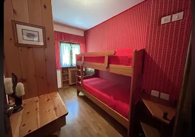 a room with two bunk beds with red walls at Ca' del Ghiaccio in Cortina dʼAmpezzo