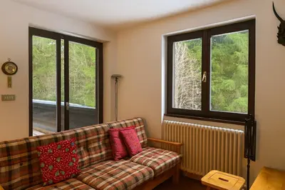 a living room with a couch and two windows at Appartamento Magico Abete by Sunhome Fiemme in Bellamonte