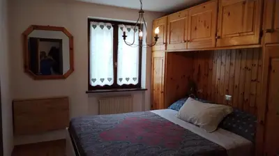 a bedroom with a bed and a mirror and a window at Via Latemar - Villaggio Veronza in Carano