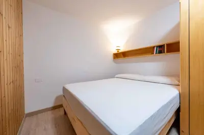 a small bedroom with a white bed and wooden shelves at Cesa Agnol in Mazzin