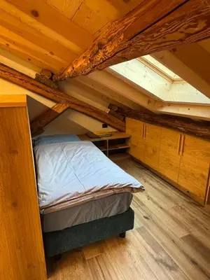 an attic room with a bed and wooden ceilings at Caluma El Paradis in Comune Rivamonte Agordino