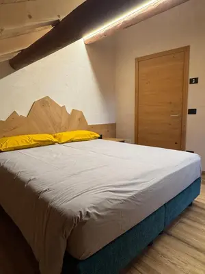 a large bed in a room with a wooden door at Caluma El Paradis in Comune Rivamonte Agordino