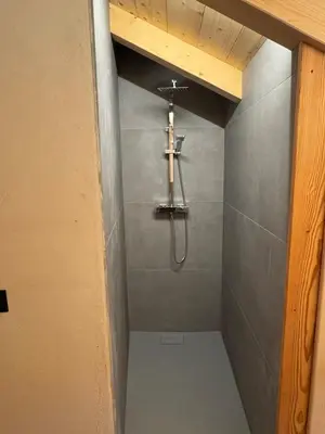 a bathroom with a shower with a cross on the wall at Caluma El Paradis in Comune Rivamonte Agordino