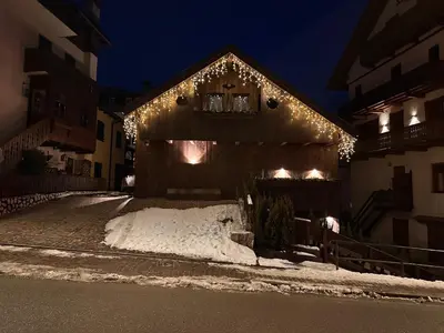 a building with christmas lights on the side of it at Fienila Luxury Spa Cortina in Cortina dʼAmpezzo