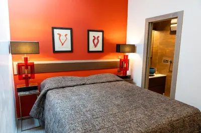 a bedroom with orange walls and a bed and two lamps at Fienila Luxury Spa Cortina in Cortina dʼAmpezzo