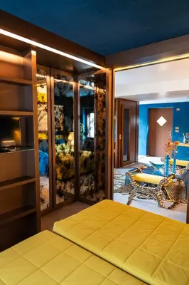 a bedroom with a yellow bed and a living room at Fienila Luxury Spa Cortina in Cortina dʼAmpezzo