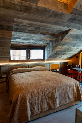 a bedroom with a large bed with a wooden ceiling at Fienila Luxury Spa Cortina in Cortina dʼAmpezzo