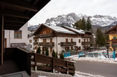 a building with snow covered mountains in the background at Fienila Luxury Spa Cortina in Cortina dʼAmpezzo