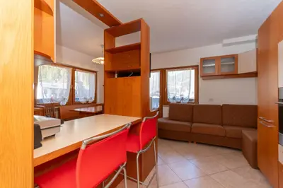 a kitchen and living room with a table and red chairs at Casa Sangi in Caviola
