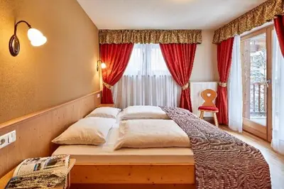 a bedroom with a large bed with red curtains at Residence Amonit in Corvara in Badia
