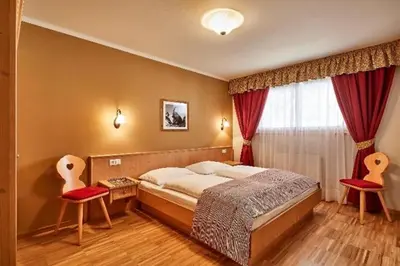 a bedroom with a bed and two red chairs at Residence Amonit in Corvara in Badia