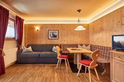 a living room with a couch and a table and chairs at Residence Amonit in Corvara in Badia