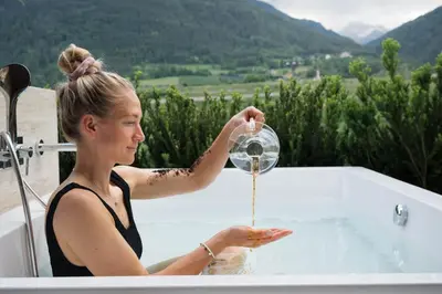a woman standing in a bath tub pouring water from a shower at Apartment Garden Loggia in Novacella