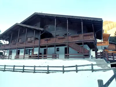 a large wooden building with a fence in the snow at Two-bedroom apartment-Casa Pieri in Penia