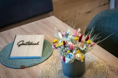 a vase of flowers on a table next to a notebook at Niederhof - Urlaub auf dem Bauernhof in Brixen