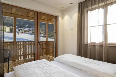 a bedroom with a bed and a balcony at Tieja Panoramic Lodge in Selva di Val Gardena