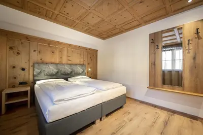 a large bed in a room with a wooden ceiling at Tieja Panoramic Lodge in Selva di Val Gardena