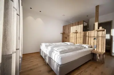 a bedroom with a large bed with a wooden headboard at Tieja Panoramic Lodge in Selva di Val Gardena