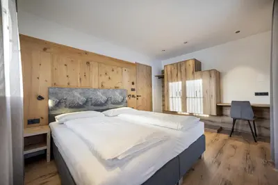 a bedroom with a large white bed with wooden walls at Tieja Panoramic Lodge in Selva di Val Gardena
