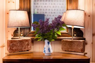 a vase of purple flowers on a table with two lamps at Wohnung GEORG-OTTO in Soprabolzano