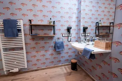 a bathroom with a sink and a wallpaper with red dolphins at Wohnung GEORG-OTTO in Soprabolzano