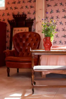 a chair and a table with a vase of flowers on it at Wohnung PAUL in Soprabolzano