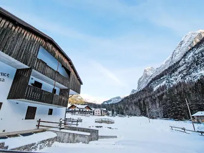 a building in the snow in front of a mountain at Apartment Apt 1 by Interhome in Penia