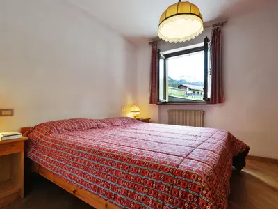 a bedroom with a bed with a red blanket and a window at Apartment Apt 1 by Interhome in Penia