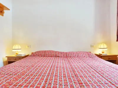a bedroom with a bed with a red bedspread at Apartment Apt 1 by Interhome in Penia
