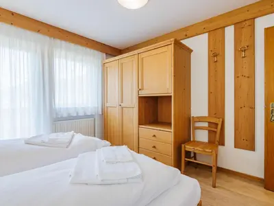 a bedroom with a bed and a wooden cabinet at Apartment Ardoney-2 by Interhome in Canazei