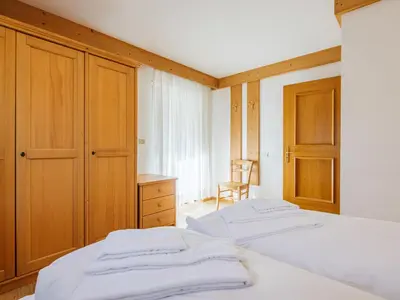 a bedroom with two beds and a cabinet and a chair at Apartment Ardoney-2 by Interhome in Canazei