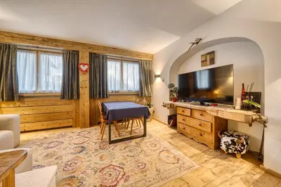 a living room with a tv and a table and a couch at Luxchalet a pochi minuti dal centro in Cortina dʼAmpezzo