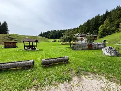 a field with a gazebo and logs in the grass at Luxchalet a pochi minuti dal centro in Cortina dʼAmpezzo