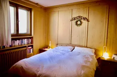 a bedroom with a bed and a book shelf at Corso Italia Apartment - Magical view of the Dolomites in Cortina dʼAmpezzo