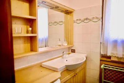 a bathroom with a white sink and a window at Corso Italia Apartment - Magical view of the Dolomites in Cortina dʼAmpezzo