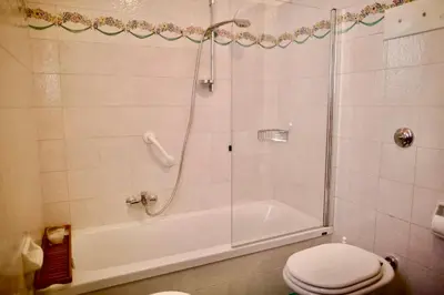 a bathroom with a shower with a toilet and a tub at Corso Italia Apartment - Magical view of the Dolomites in Cortina dʼAmpezzo
