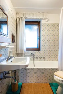 a bathroom with a sink and a tub and a window at Villa Diana in Cortina dʼAmpezzo
