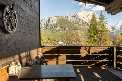 a table on a balcony with a view of mountains at Villa Diana in Cortina dʼAmpezzo