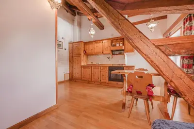 a kitchen with wooden cabinets and a table at Ca' Alpini - Mountain View Terrace & Parking in Cortina dʼAmpezzo