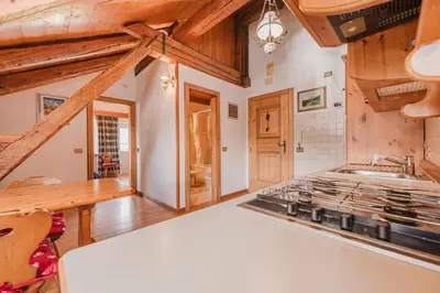 a kitchen with wooden ceilings and a stove at Ca' Alpini - Mountain View Terrace & Parking in Cortina dʼAmpezzo