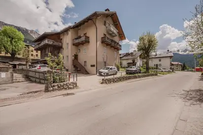a house on the side of a road with a car parked at Ca' Alpini - Mountain View Terrace & Parking in Cortina dʼAmpezzo