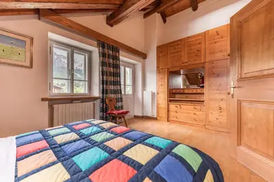 a bedroom with a bed and wooden cabinets and a tv at Ca' Alpini - Mountain View Terrace & Parking in Cortina dʼAmpezzo