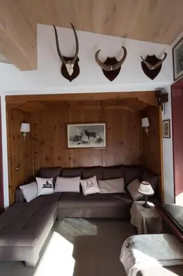 a living room with a couch and antlers on the wall at Cortina Olympics cosy apartment in Cortina dʼAmpezzo