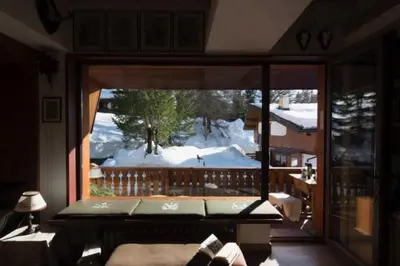 a bedroom with a view of a snow covered yard at Cortina Olympics cosy apartment in Cortina dʼAmpezzo