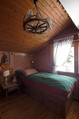 a bedroom with a bed with a window and a chandelier at Cortina Olympics cosy apartment in Cortina dʼAmpezzo