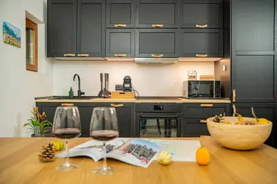a kitchen with black cabinets and a wooden table with wine glasses at MH Luxury Apartments in Cavalese