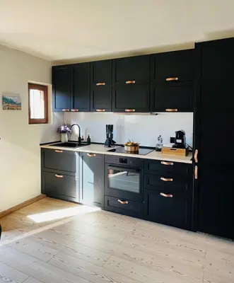 a kitchen with black cabinets and a wooden floor at MH Luxury Apartments in Cavalese