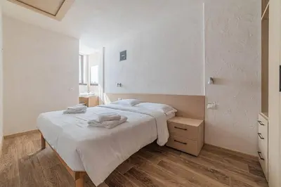 a white bedroom with a large bed with towels on it at Casa Scola in Falcade