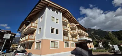 a large building with a car parked in front of it at Casa Aloch da Aldo Gianni in Pozza di Fassa